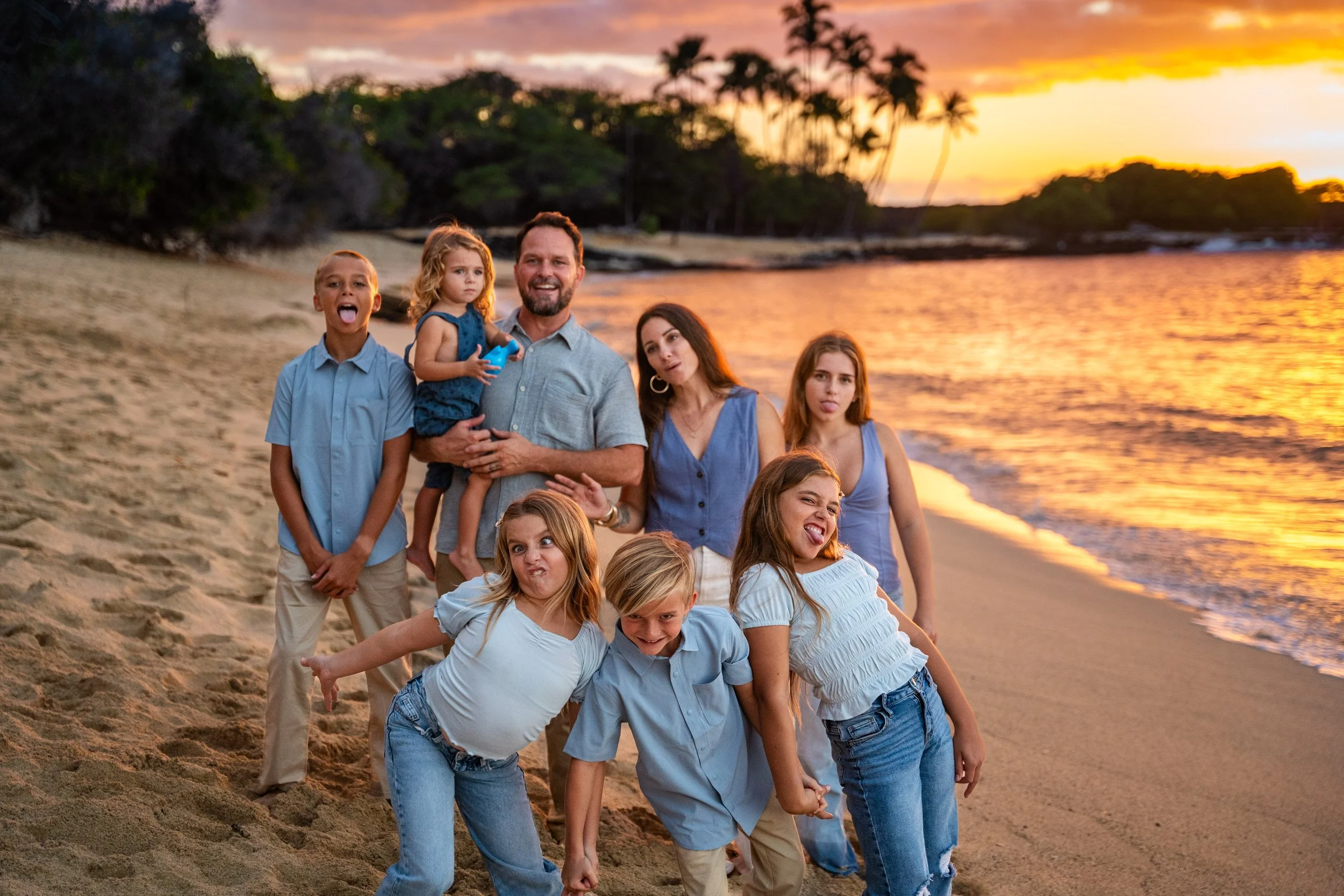 Family of seven laughing and making silly faces during a playful sunset photo session at Mahaiʻula Beach on the Big Island of Hawaii.