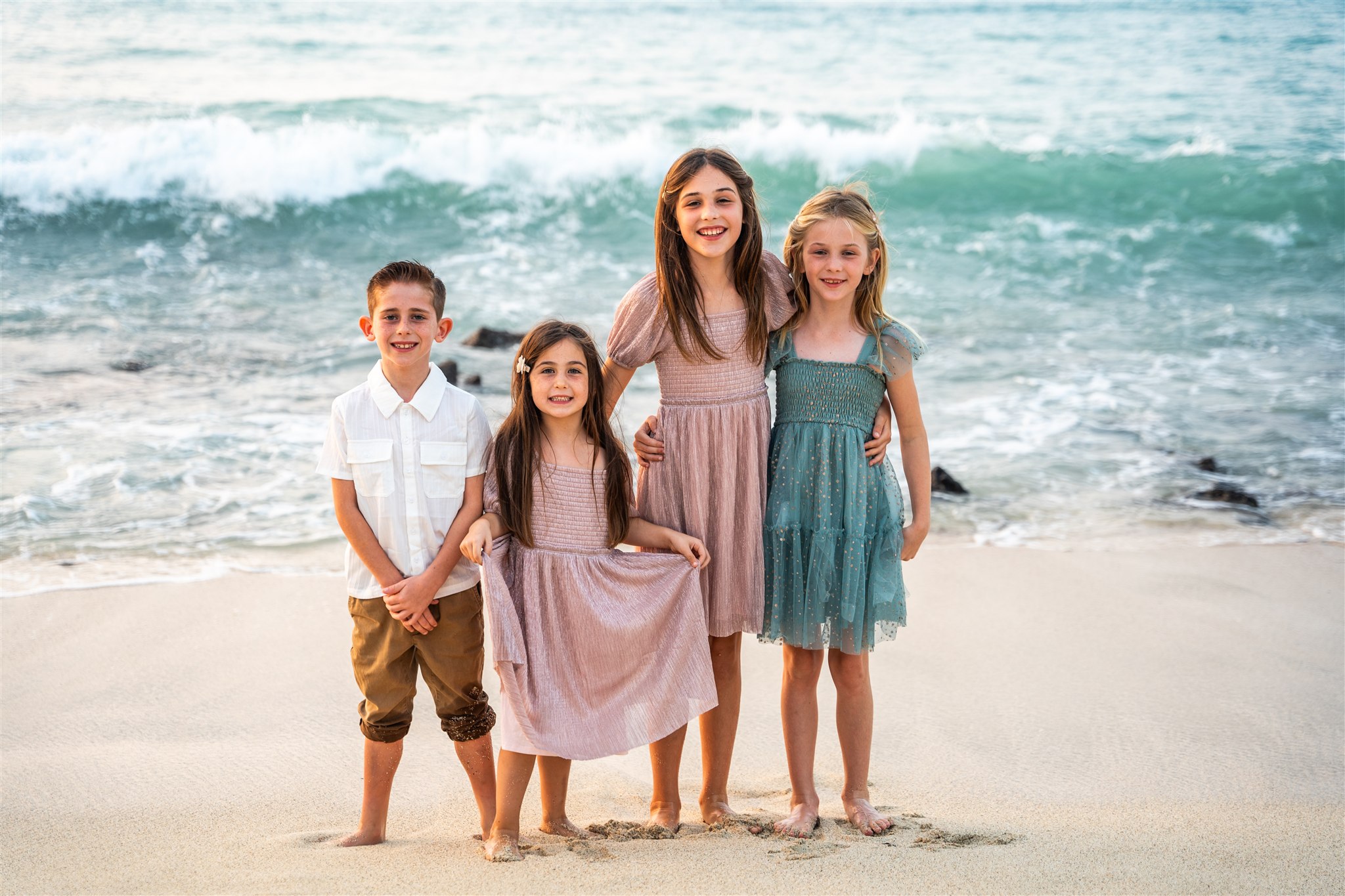 beach family portraits in hawaii with siblings in pink, white, and blue