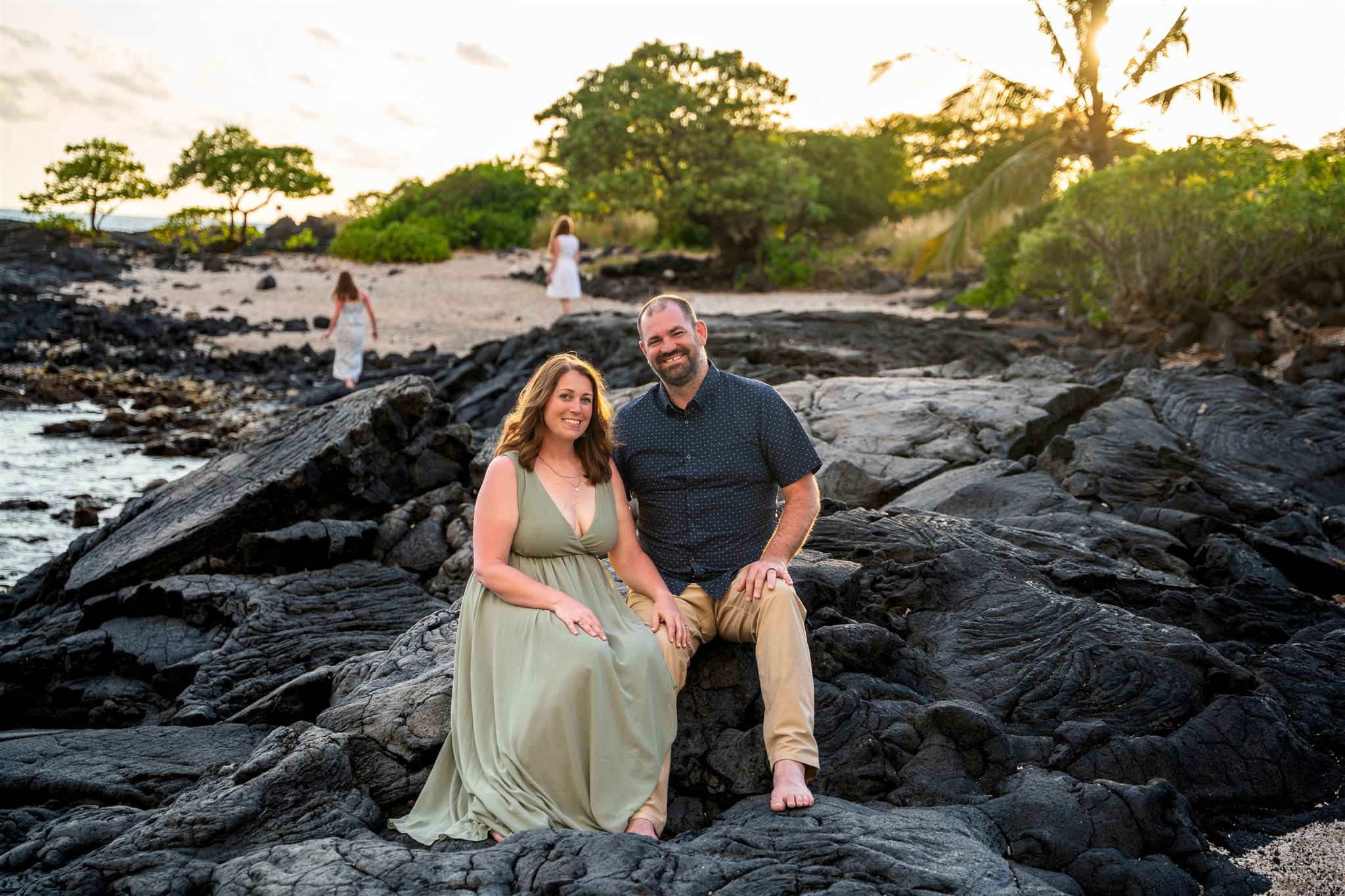 beach hawaii family portraits with parents in the center and kids playing behind them