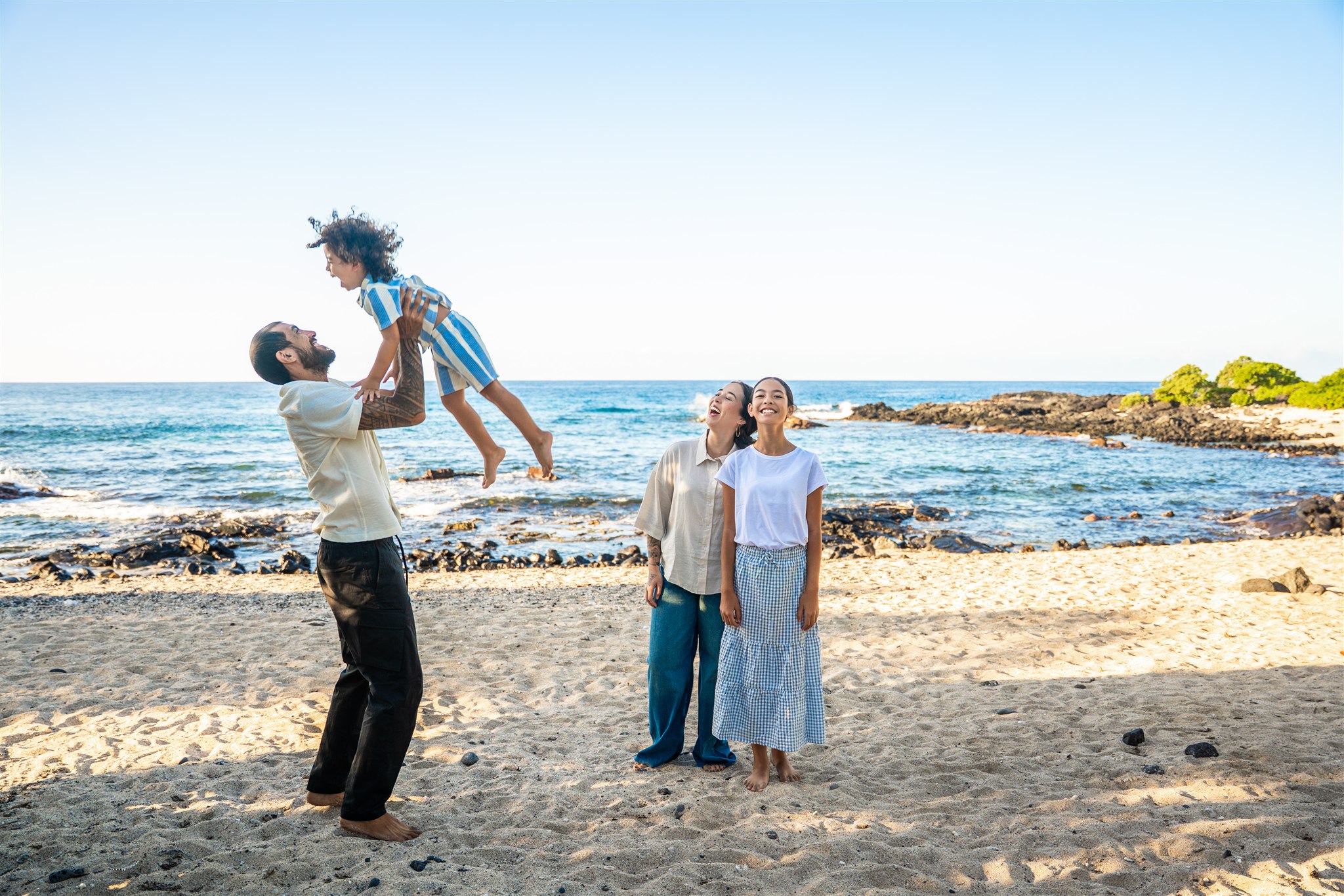 kids being lifted on the beach for family portraits in hawaii