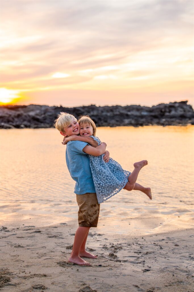 sunset hawaii family photo ideas with siblings hugging each other