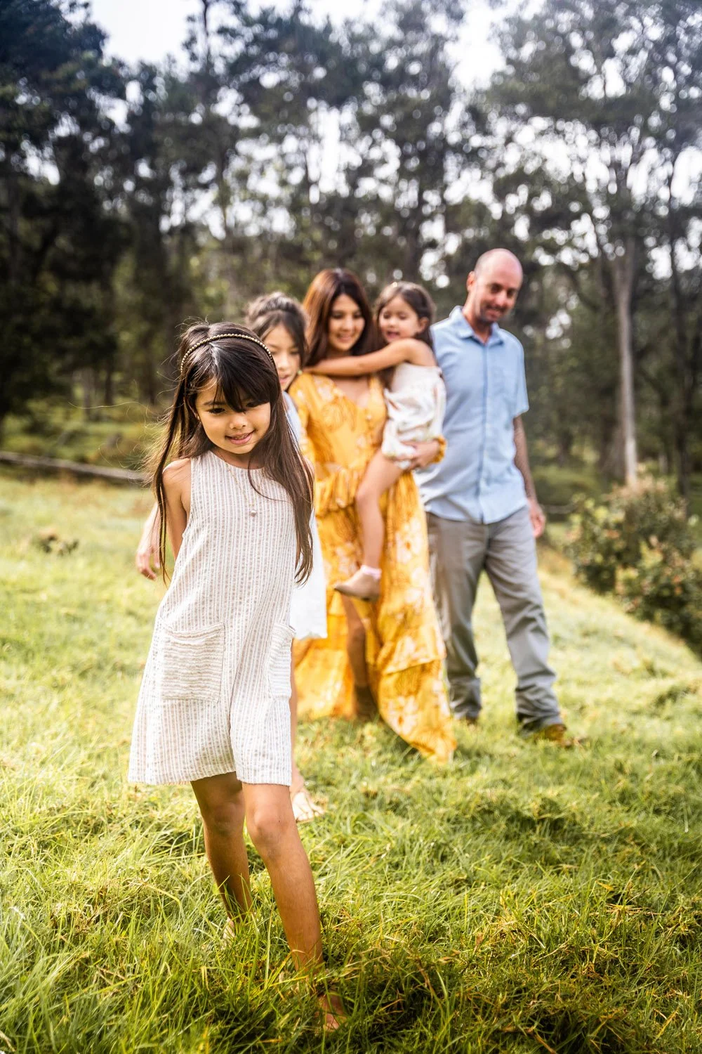 family walking through a forest with their little girls leading them in kailua kona on the big island of hawaii