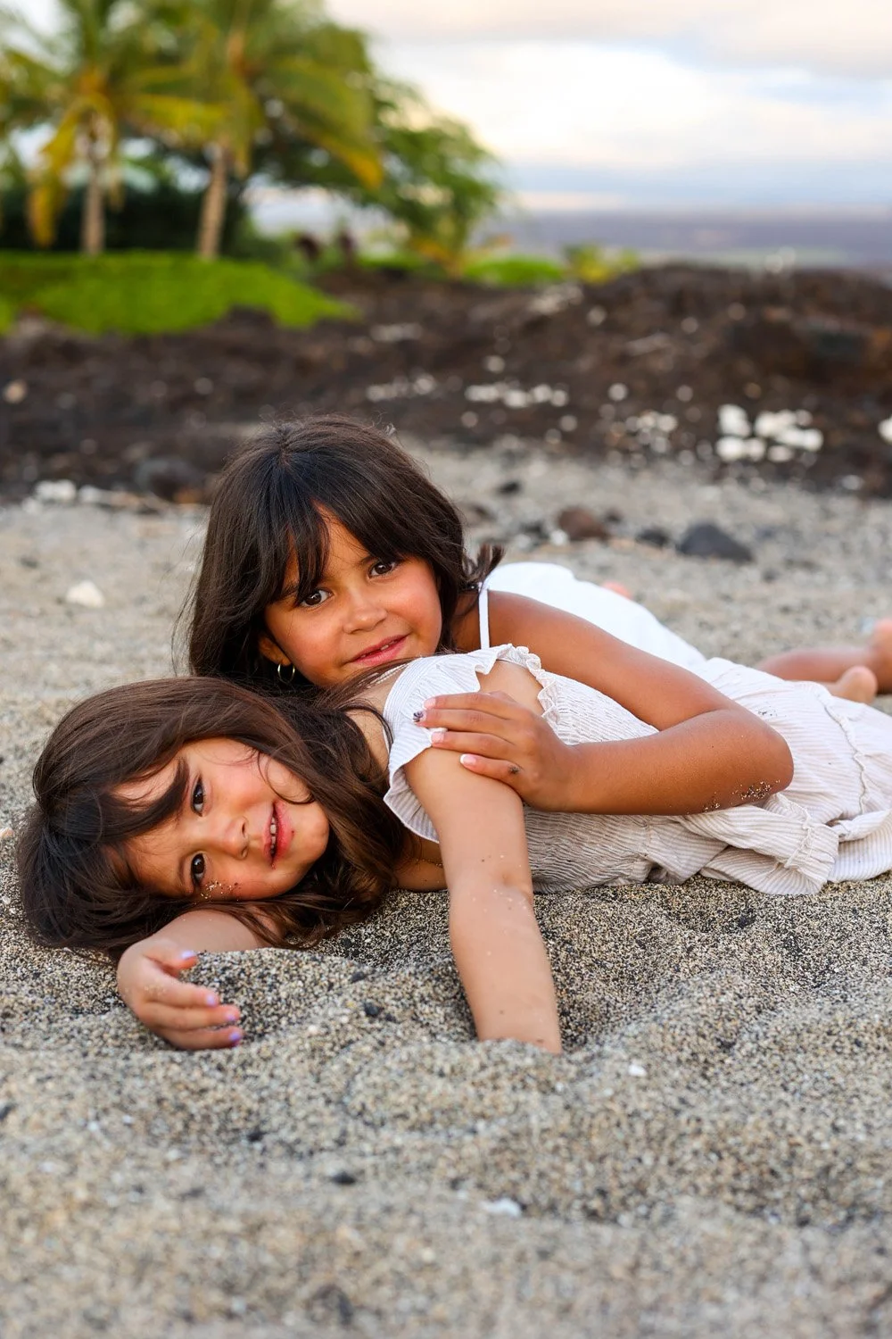 sisters playing on a white sandy beach on the big island of hawaii