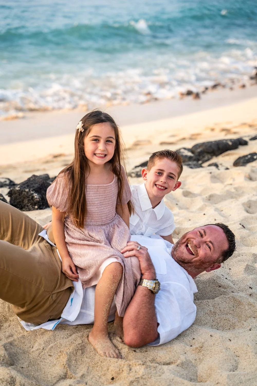 Father playing with his children on a white sandy beach in Hawaii