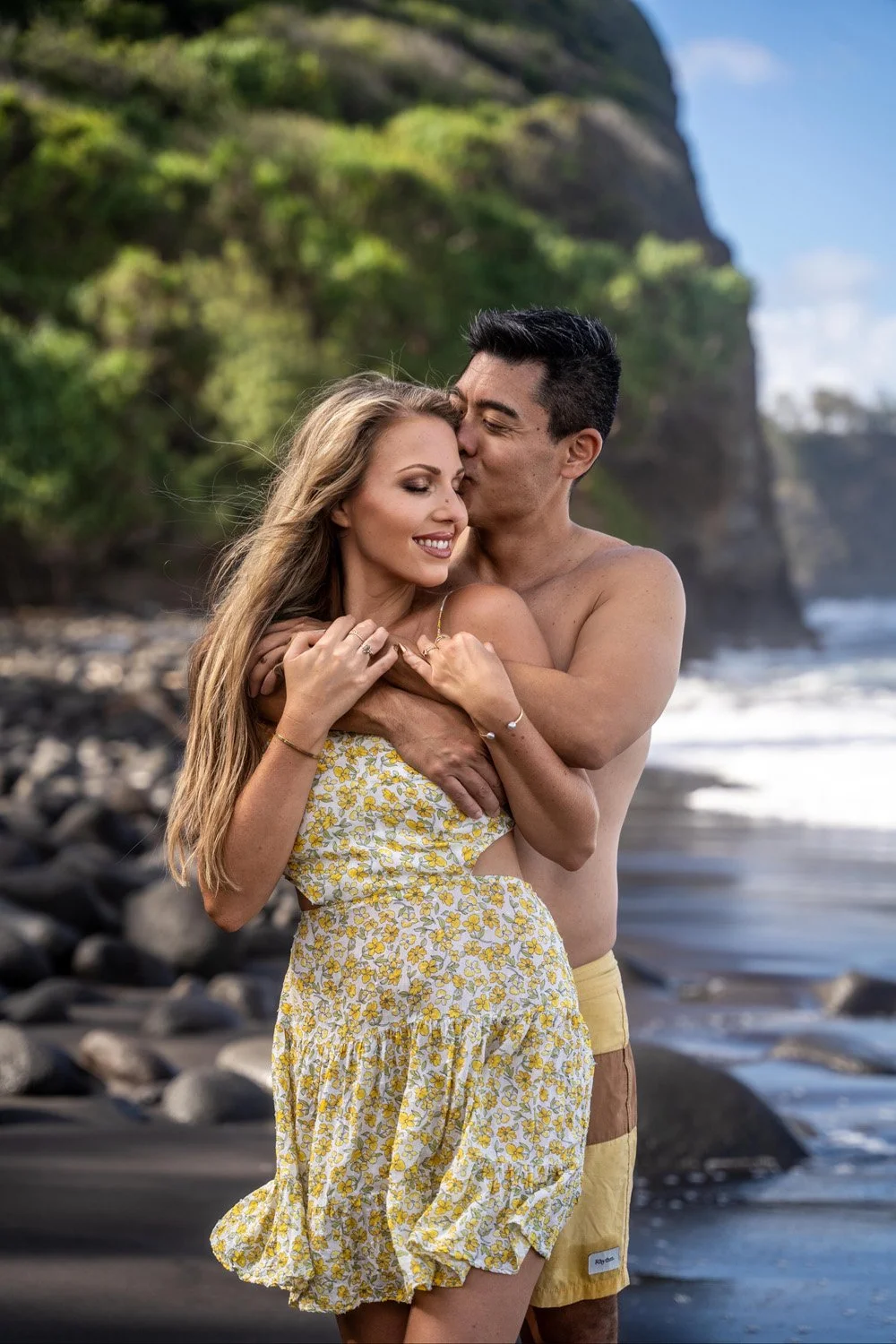 couple holing each other on a black sandy beach for a couples portrait session on the Big Island of Hawaii