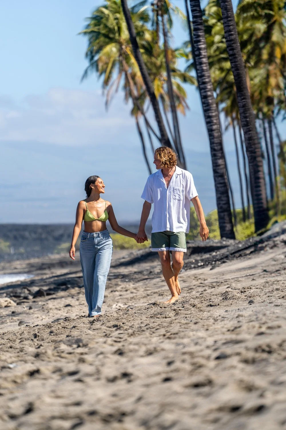 couple running on a beach with palm trees in the background for a couples portrait session on the Big Island of Hawaii