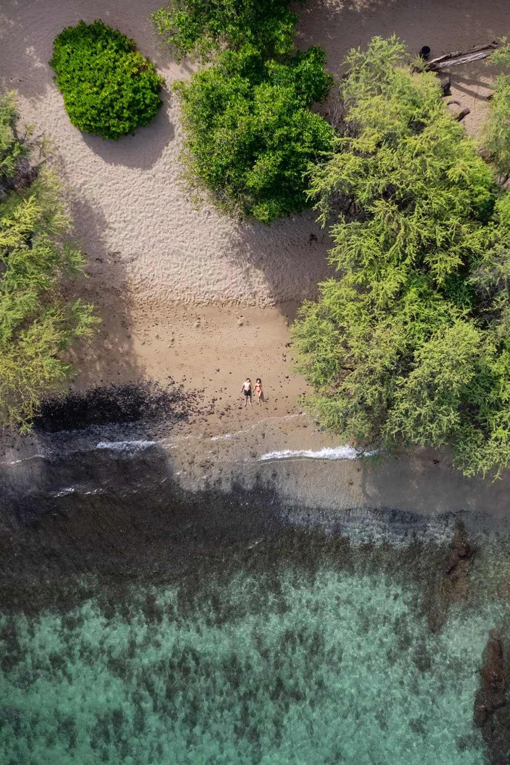 couple holding hands on a white sandy beach drone aerial photography for a couples portrait session on the Big Island of Hawaii
