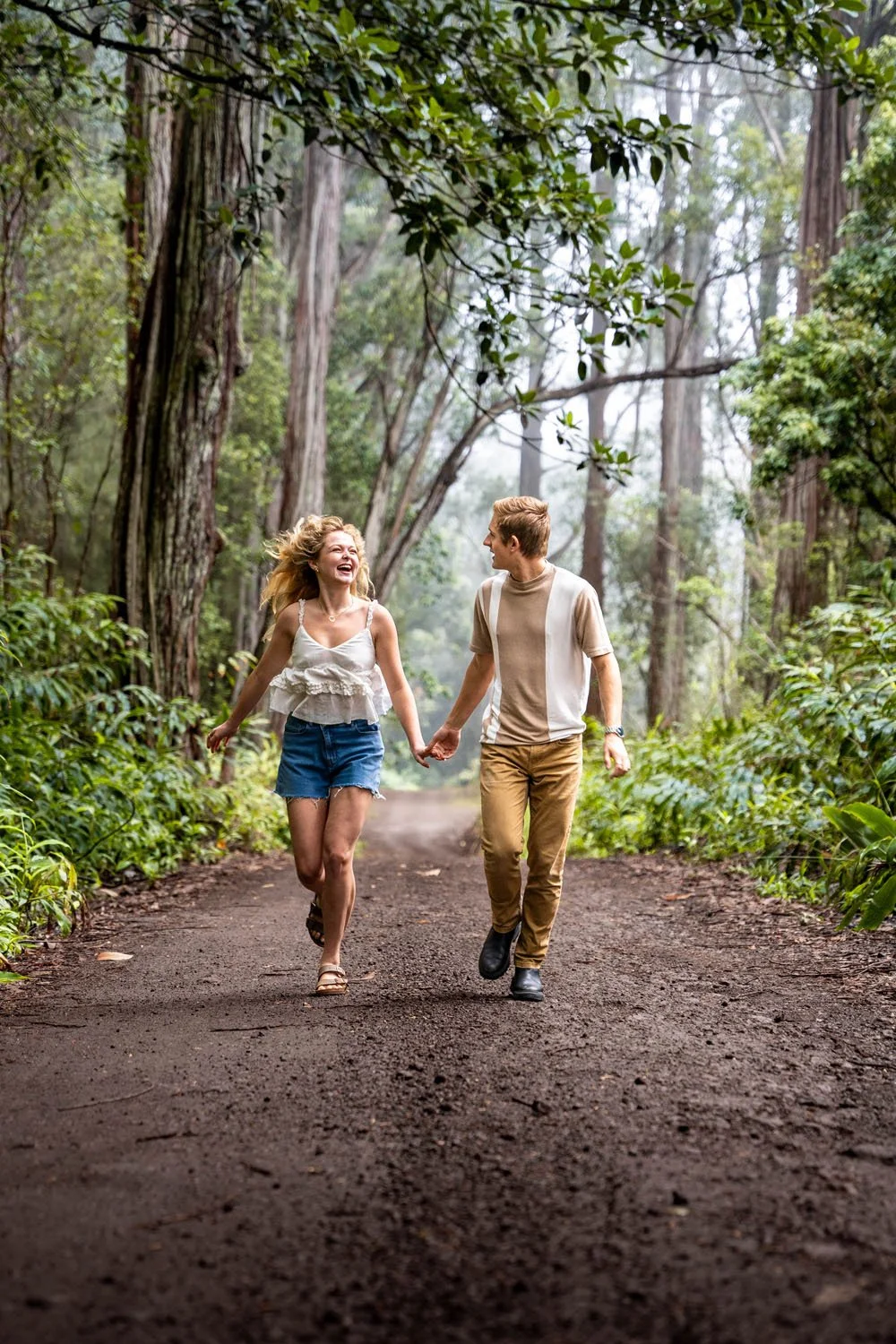 couple running holding hands through a jungle forest for a couples portrait session on the Big Island of Hawaii