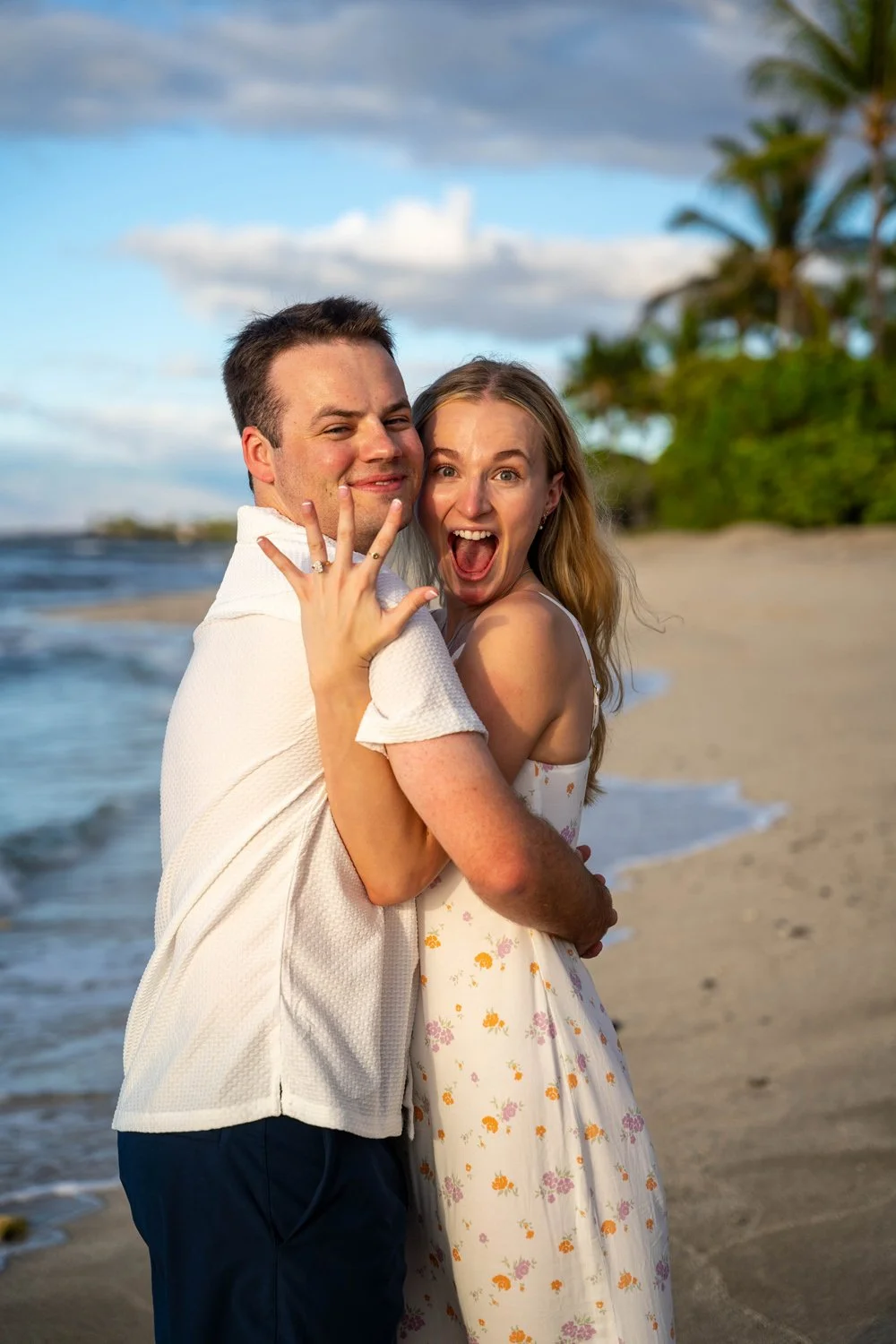 couple embracing with excitement after a surprise proposal at the four seasons hualalai resort for a couples portrait session on the Big Island of Hawaii