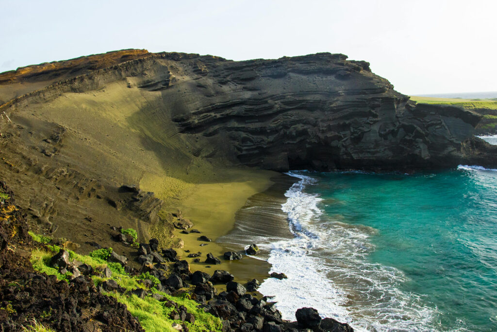 Papakōlea Green Sand Beach on the Big Island of Hawaii, showing rare green sand and turquoise water during a Volcanoes National Park day trip from Kona.
