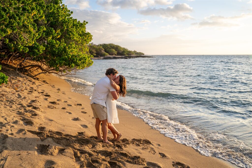 Couple kissing on the beach at sunset after a surprise proposal in Waikoloa, Big Island Hawaii