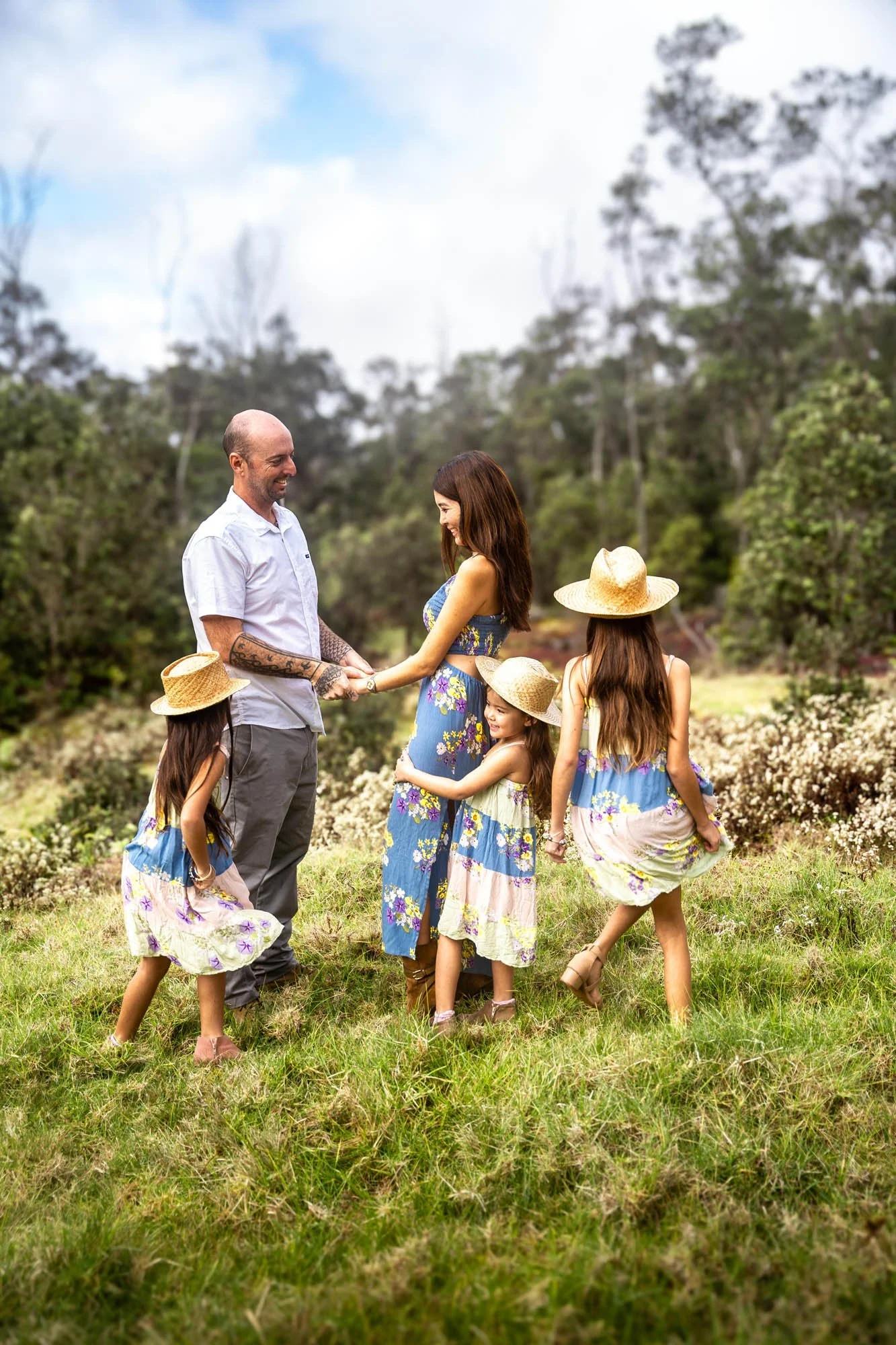 Family holding hands and walking through a grassy field during a Hawaii family photo session.