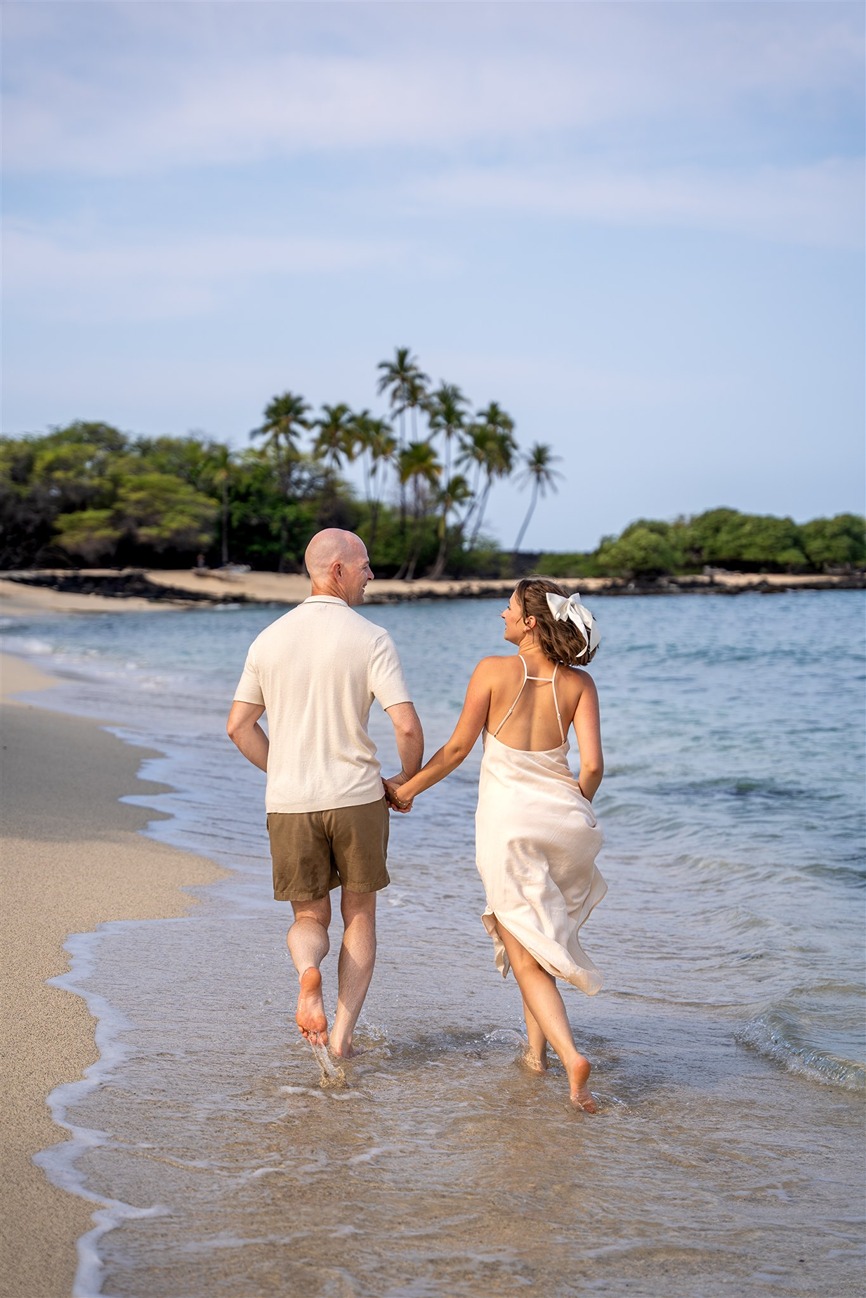 ​engagement pictures in hawaii of the couple running on the beach