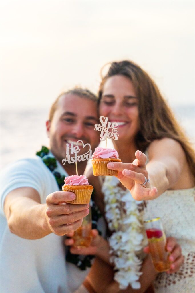 couple holding engagement cupcakes by hawaii proposal photographer
